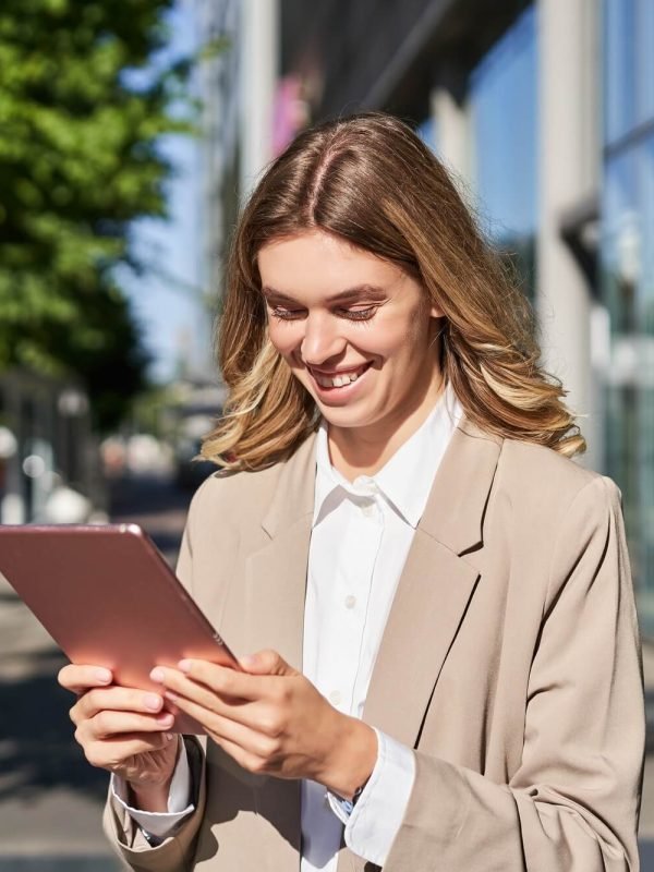 portrait-of-happy-businesswoman-smiling-holding-digital-tablet-on-street-near-office-building.jpg